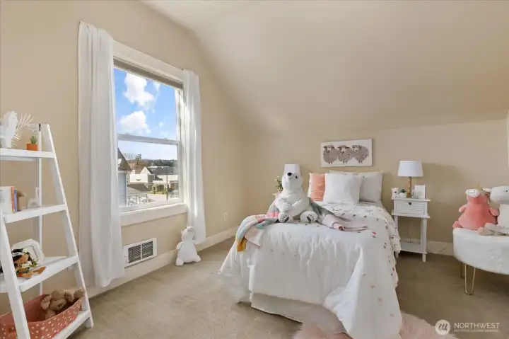 Bright and cheerful, this bedroom features a large window that frames views of the surrounding neighborhood and sky.