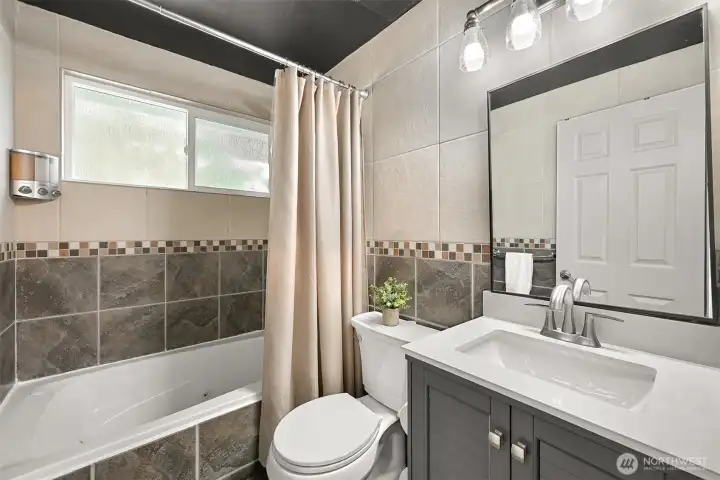 Updated full bath with modern vanity, tile surround, and natural light.