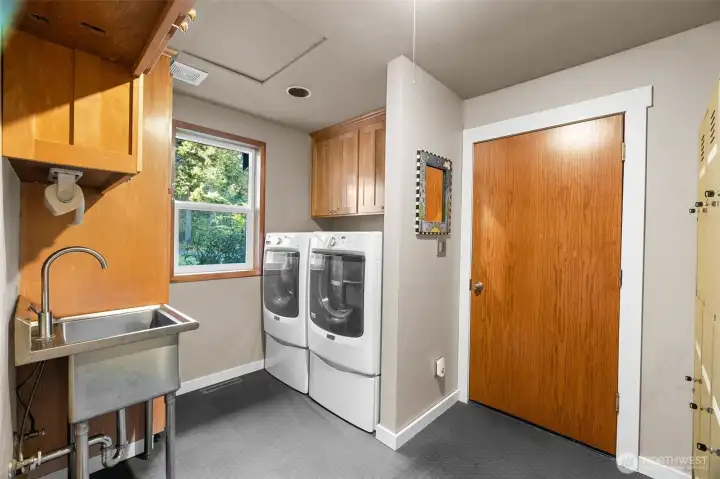 Main floor laundry room/mud room adjoins the garage. It features plenty of storage with a sturdy stainless utility sink plus rubber floors for durability and easy cleaning