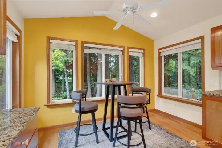 The informal dining area is surrounded by windows and the natural forested setting.