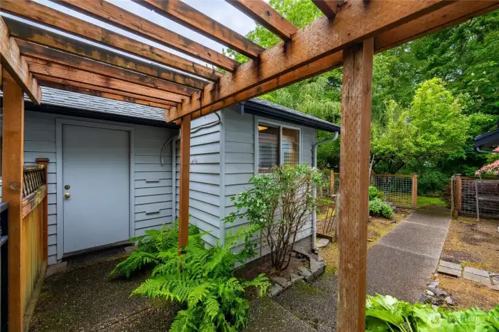 Walking from the garage to the detached work shop with the trellis above and the garden fence beyond.