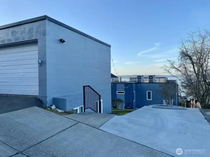 One parking space with steps down to Unit C front door. You can see Units A and B right in front. Garage door to the left. Currently used for parking one vehicle and storage.