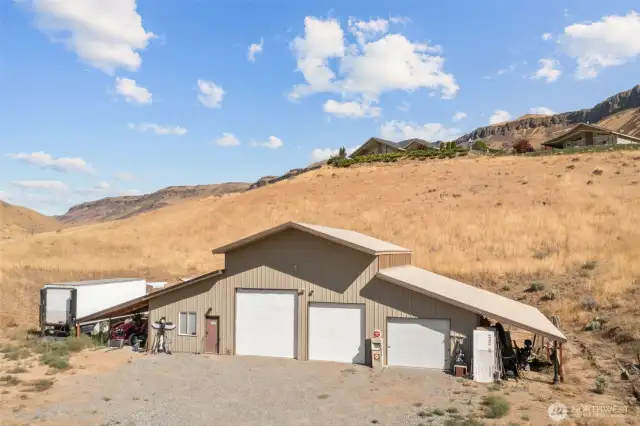 Massive show with multiple bays, work area, and carports on the sides. The shop has a separate driveway (and address) and sits below the house.