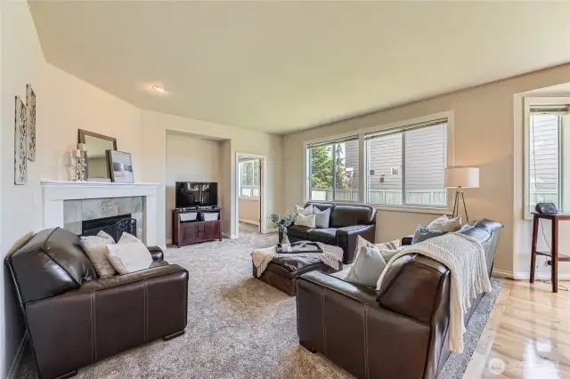This inviting family room offers a warm and welcoming space ideal for both relaxation and entertaining. Bathed in natural light from large windows, the room features an open layout that seamlessly connects to the kitchen and eating space. A stylish blend of plush carpet and gleaming hardwood floors adds texture and comfort, creating a cozy yet refined ambiance. With ample room for seating and easy access to the backyard through sliding glass doors, this space is perfect for movie nights, casual gatherings, and everyday living.