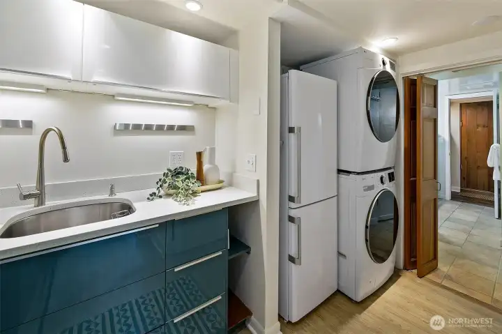 Stacked laundry is right outside the 3/4 bath, and the wood door beyond is the sauna.