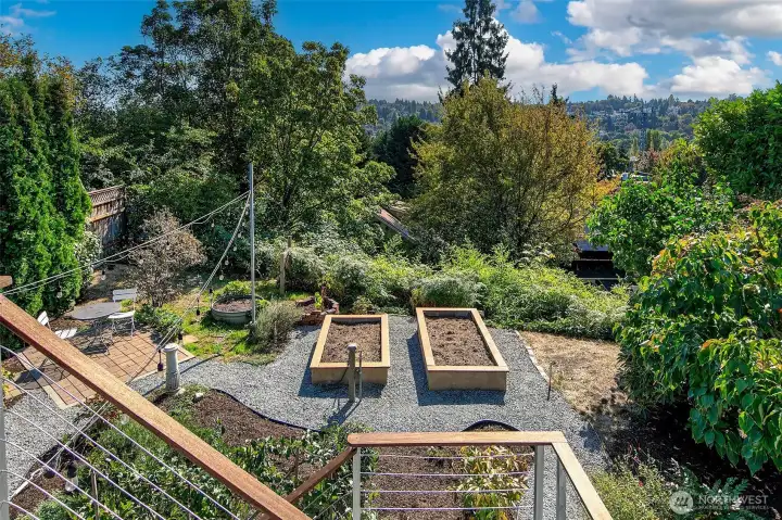Raised veggie beds, established perennials, and an espaliered fruit tree await some spring & summer abundance.
