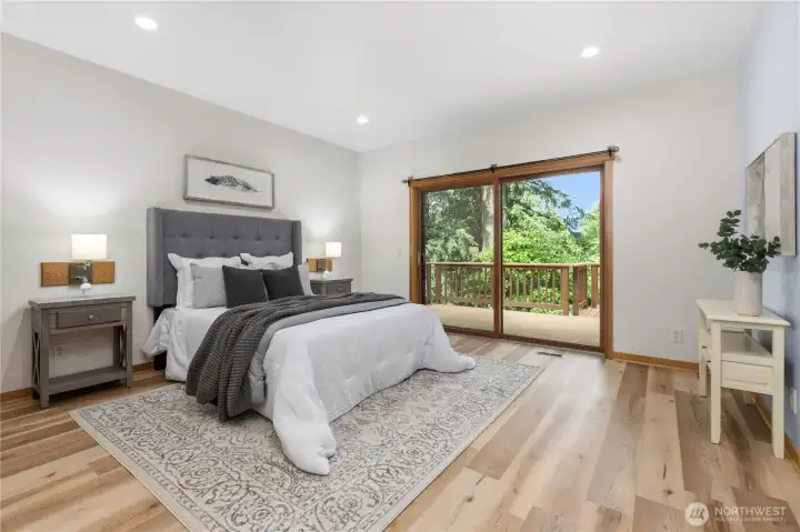 The main-level primary suite offers generous proportions, deck access, and views of the surrounding natural landscape. The main-level primary suite offers generous proportions, deck access, and views of the surrounding natural landscape.