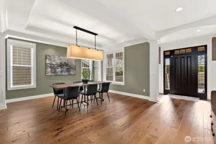 Spacious formal dining room with hardwood floors, tray ceiling, large windows, and designer lighting—perfect for entertaining family and friends in this open-concept Kirkland residence.