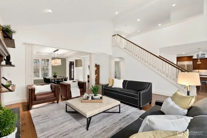 Open living room with dramatic ceilings, large picture windows, and effortless connection to the kitchen, dining area, and outdoor living spaces.