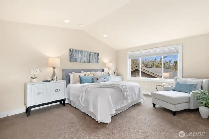 Generous primary suite features vaulted ceilings, oversized windows, abundant natural light, and ample space for a sitting area, creating a peaceful private retreat.