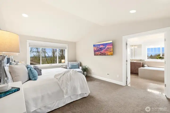 Luxurious primary bedroom offers serene neighborhood views and direct access to a spa-inspired ensuite bath with dual vanities, soaking tub, and walk-in shower.