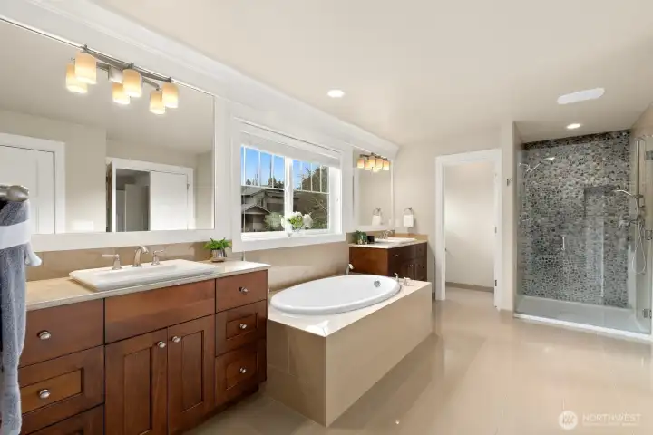Luxury primary bath features a frameless glass walk-in shower with designer stone tile, soaking tub, dual sinks, and spacious walk-in closet access.