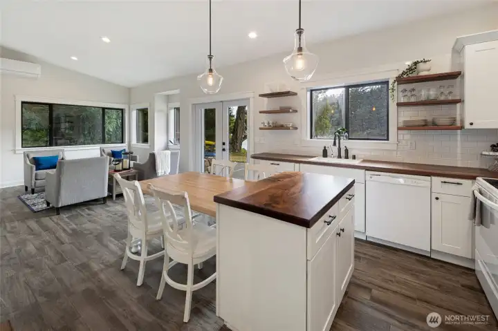 Thoughtfully renovated kitchen features shaker cabinetry, butcher block countertops, subway tile backsplash, center island, and an open dining area designed for comfortable everyday living.