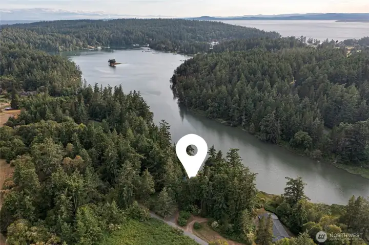 Aerial perspective highlighting the property's peaceful waterfront setting on Mitchell Bay, surrounded by evergreen forest and calm protected waters with convenient access to San Juan Island's west side.