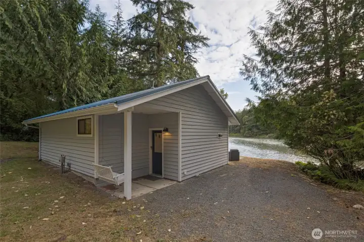 Charming cottage featuring low-maintenance siding, covered front porch with swing, metal roof, and peaceful waterfront setting.