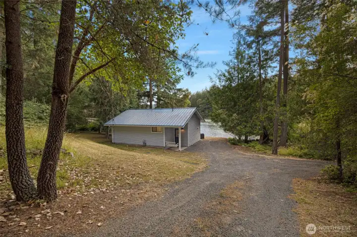 Private gravel driveway welcomes you through mature evergreens, creating a peaceful arrival to this secluded waterfront retreat.