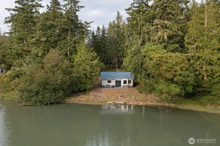 The cozy waterfront cottage enjoys exceptional privacy with direct shoreline access, mature landscaping, and a peaceful natural setting.