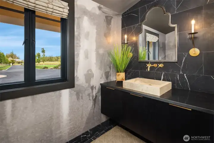 Powder bath features a floating vanity with travertine sink, Phylrich wall faucets, marble accent wall and floors with radiant heated floors.