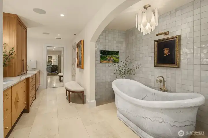 Primary bath features Italian marble bathtub with zellige tile tub surround and vanity backsplash, walk-in shower, custom cabinetry, and quartzite countertops.  Floors feature travertine and radiant floor heat.  The full mirror is a secret door to the home gym.