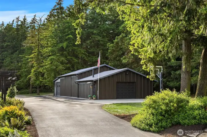 Barn/workshop with extra parking.  There are three bays with electric garage doors (middle bay garage door is behind sliding entry).  Large center bay could be used as a workshop, studio, boat or RV parking.  Also features a built-in basketball hoop which is adjustable in height.