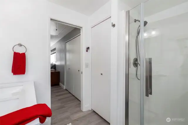 Primary   bath with linen closet and glass shower door.