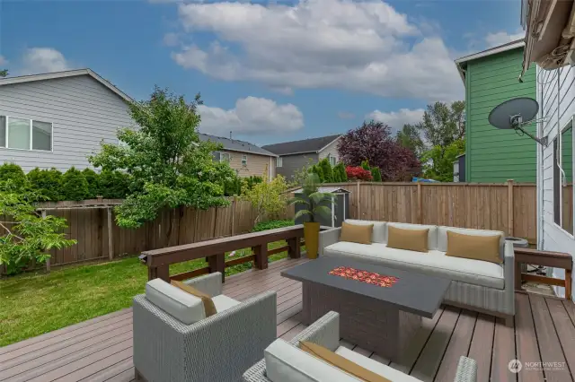 Staged. The fenced backyard features fruit trees, perennial flowers, garden beds, and a patio.