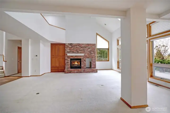 From the kitchen looking into the great room/living room with plenty of light and beautiful brick fireplace wall with wood stove insert.