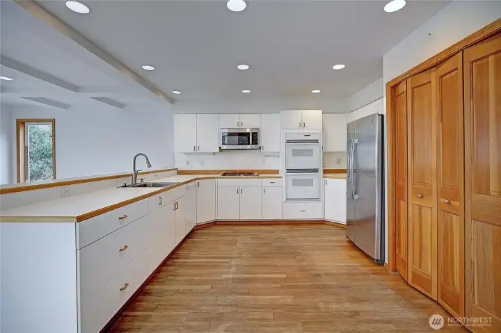 Kitchen with plenty of ceiling lights, pantry and refrigerator.