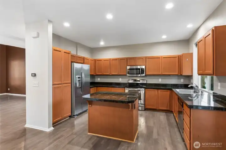 Kitchen view one, formal dining room is to your left. Granite tile countertops, included stainless steel appliances, and look at all those outlets! Great cabinet space as well.