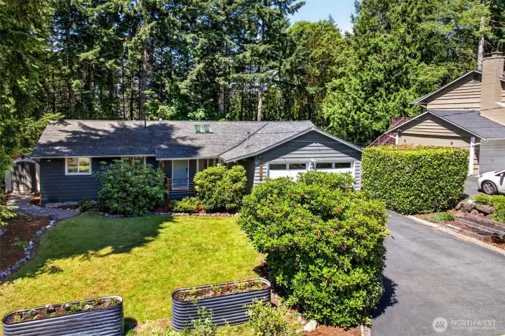 A single-level home backed by towering evergreens offers a true sense of Pacific Northwest privacy and retreat, while the level lawn and raised garden beds set the stage for easy outdoor living.