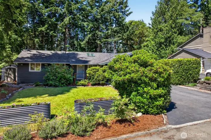Established landscaping and tidy raised planters wrap the property in greenery, with a separate storage shed to handle tools and seasonal gear so the garage stays open for vehicles.