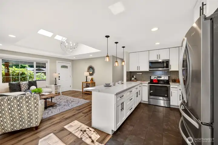 The updated kitchen anchors the home's open core with crisp white cabinetry, quartz counters, and stainless appliances, and the peninsula keeps seating and prep space within easy reach of the living and dining areas.
