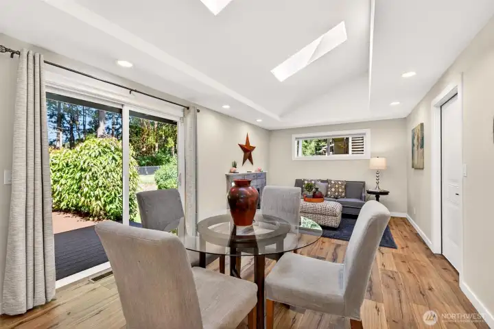 A sunlit dining space sits beside the slider to the back deck, making warm-weather meals and indoor-outdoor entertaining a natural part of daily life, with a cozy fireplace just steps away.