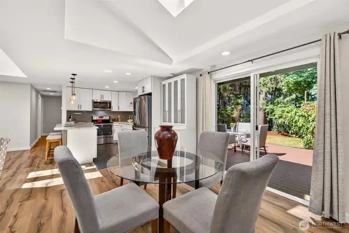 Glass-front display cabinetry adds both storage and style to the dining area, while the slider frames the deck and wooded backyard for an easy connection to the outdoors.