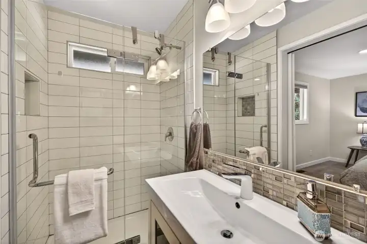 The updated bath pairs a glass-enclosed tiled shower with a sleek vanity and glass-mosaic accent, delivering a spa-like feel in a low-maintenance, move-in-ready package.