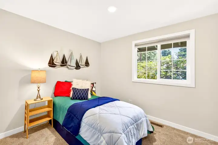 A versatile bedroom filled with natural light looks out over garden greenery, ready to serve as a sleeping space, study, or hobby room to suit your needs.