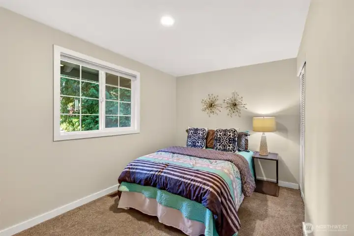 A peaceful bedroom framed by a divided-light window overlooks the leafy surroundings, offering a calm retreat with closet space ready for everyday organization.