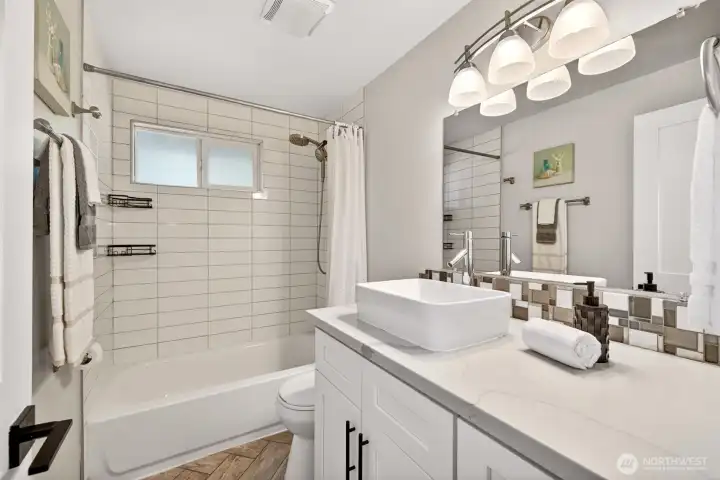 The full bath blends a tiled tub and shower with a stylish vessel sink and quartz-topped vanity, giving daily routines a fresh, comfortable place to start and end the day.