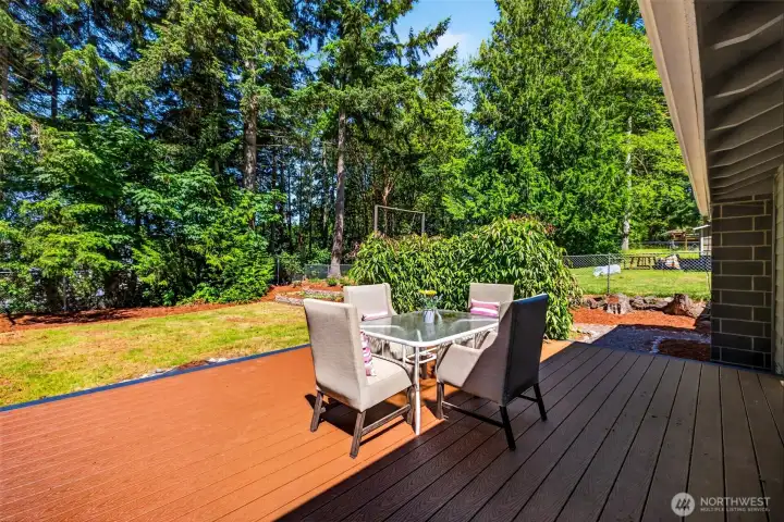 The composite deck extends the living space outdoors, creating a private spot to dine or relax while taking in the lush evergreen backdrop.