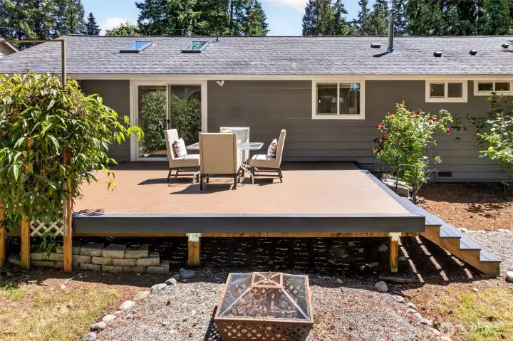 A spacious composite deck steps down to a gravel fire pit area, giving you room to entertain, gather around the fire, and enjoy the wooded yard through every season.