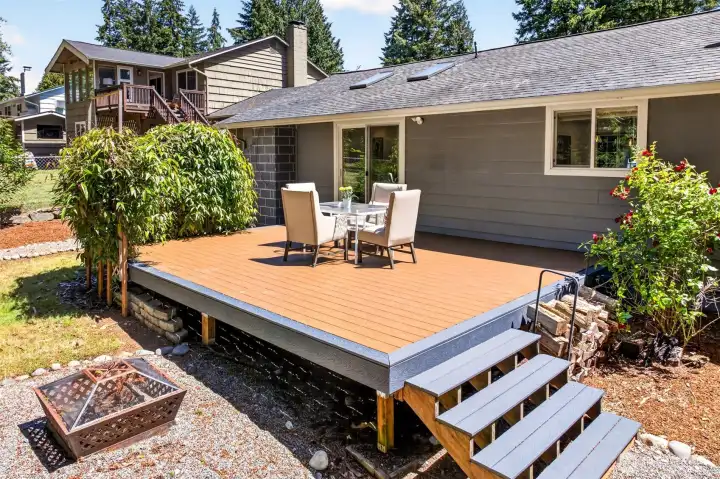 The low-maintenance deck connects directly to the home through the slider, with a fire pit and open yard just beyond for effortless indoor-outdoor living.