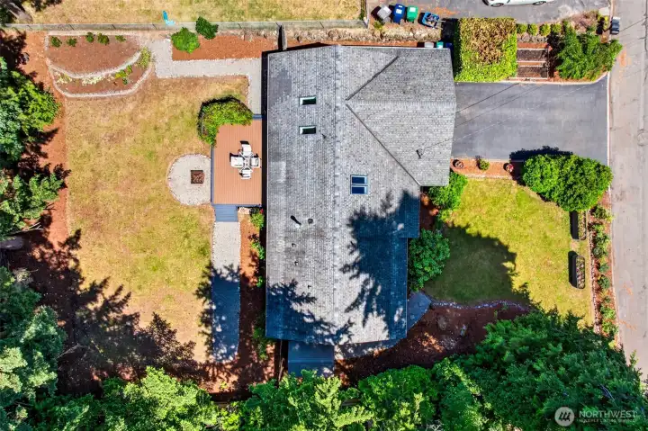 An overhead view reveals the home's generous lot, with the deck, fire pit, lawn, and garden beds thoughtfully arranged for relaxed outdoor living and easy upkeep.