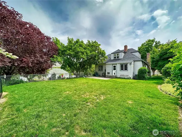 Level and fenced back yard space with mature plantings