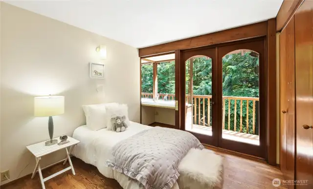 Bedroom 1 on the upper level with built-in desk and access to the creek-facing balcony.