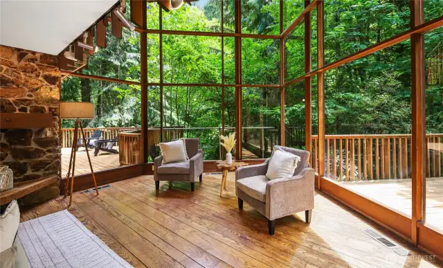 The living room with dramatic 20 foot tall walls of glass looking out towards Boeing Creek Park.