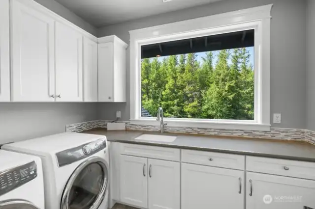 Upstairs laundry room with pretty views and utility sink.