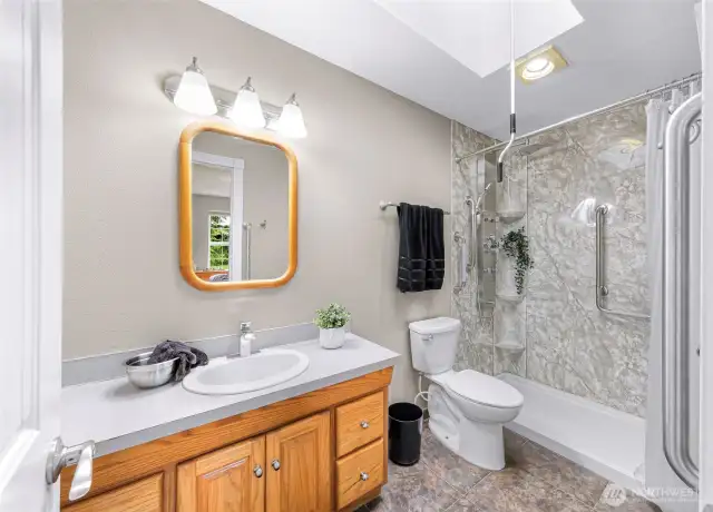 Big open shower area, with handle bars throughout and bench for sitting.