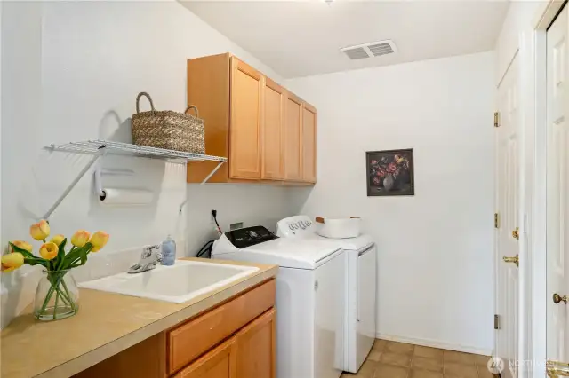 Conveniently located on the main floor, the utility room offers a deep sink, generous cabinets, and a closet for organized storage.