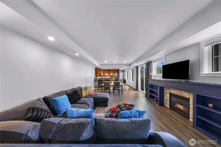 Expansive great room with a gas fireplace, built-ins, large windows, and a seamless flow into the dining and kitchen areas.