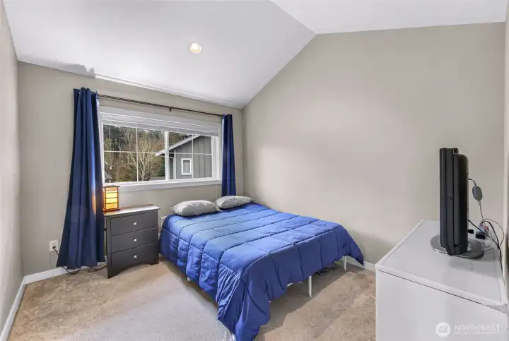 Upper level bedroom with vaulted ceilings and a large window that brings in great natural light.